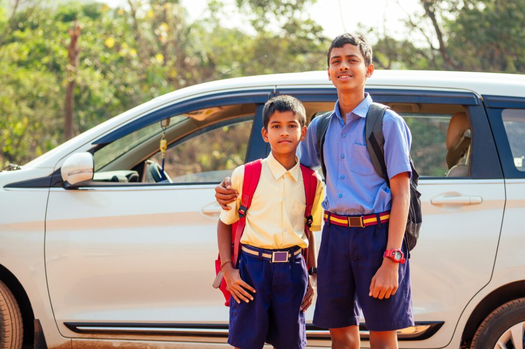 two indian boys ready to go to school on the car